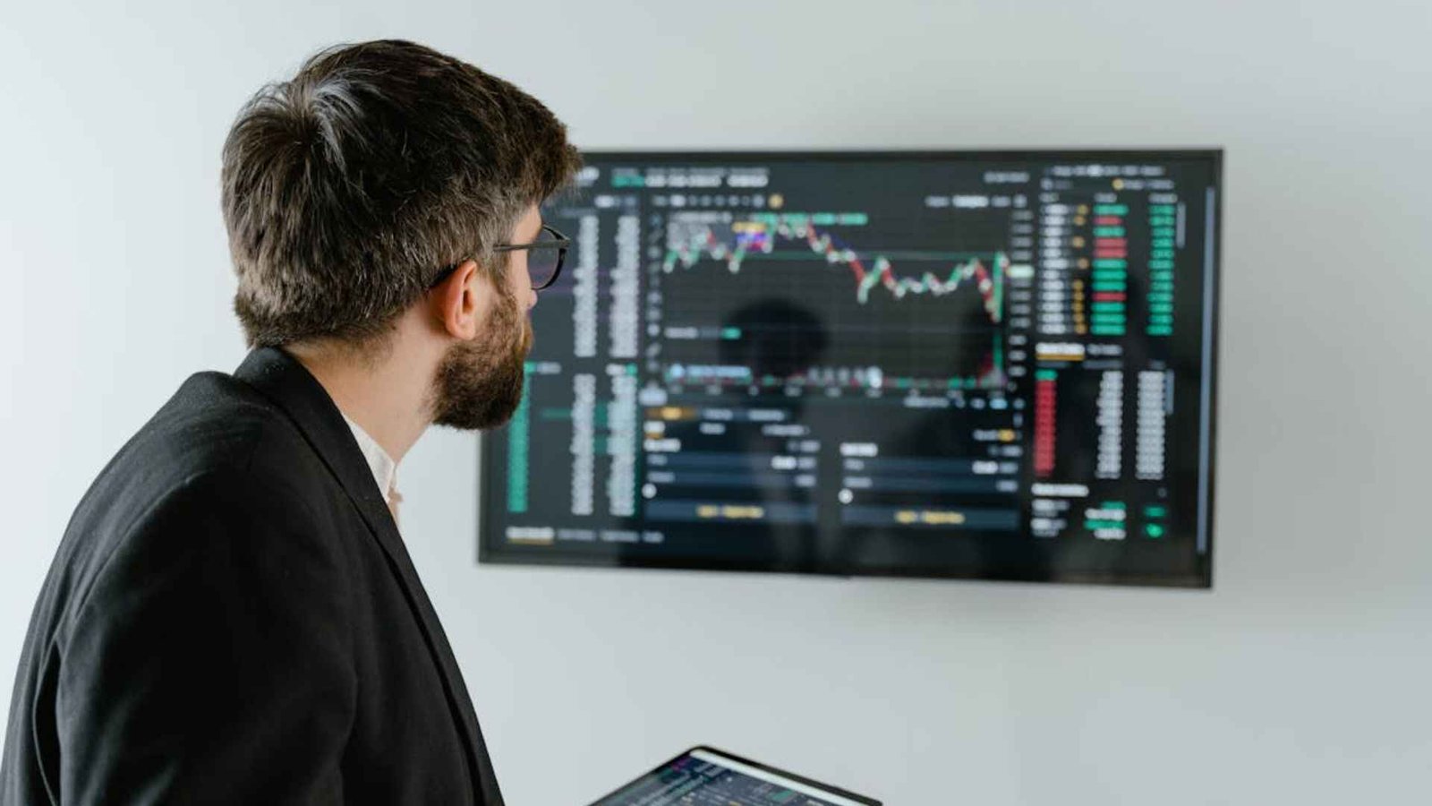 Image Of Man in Black Suit Holding a Digital Tablet and Looking At Data On Screen Representing Adobe Stocks Fall 12.1% After Leadership Shift