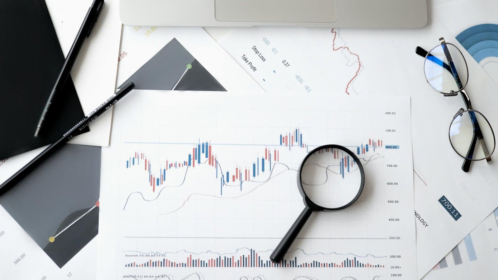 A magnifying glass over volatile stock market charts, symbolizing Prof G's $10T wipeout warning and the deep analysis required for investors to navigate the 2026 market crisis.